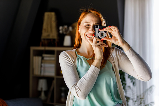 Happy young woman using analog camera.