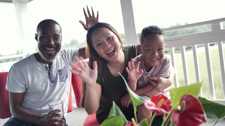 Multiracial family with young boy on porch, look at camera