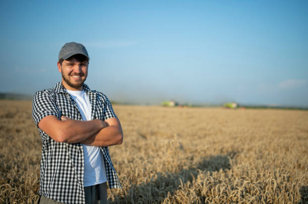 istock Smiling farmer on the wheat field on harvest. 1556878274