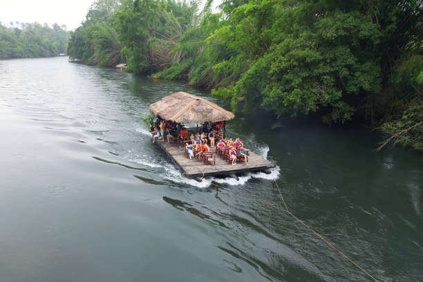vista superior do barco de cauda longa arrastando jangada de madeira perto da cachoeira que flui no rio kwai kanchanaburi - rafting thailand river inflatable raft - fotografias e filmes do acervo