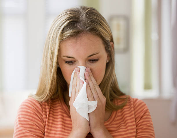 istock Young blond woman blowing her nose into a tissue 155688932