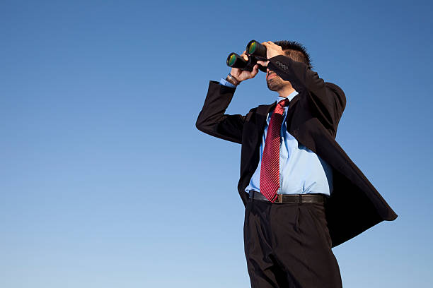 Businessman looking through binoculars Businessman looking through binoculars with a blue sky as background binoculars photos stock pictures, royalty-free photos & images