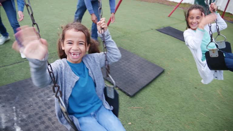 Multiracial family playing on swings at playground