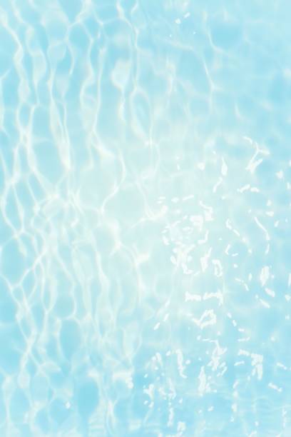 istock Blue water with ripples on the surface. Defocus blurred transparent blue colored clear calm water surface texture with splashes and bubbles. Water waves with shining pattern texture background. 1556972995