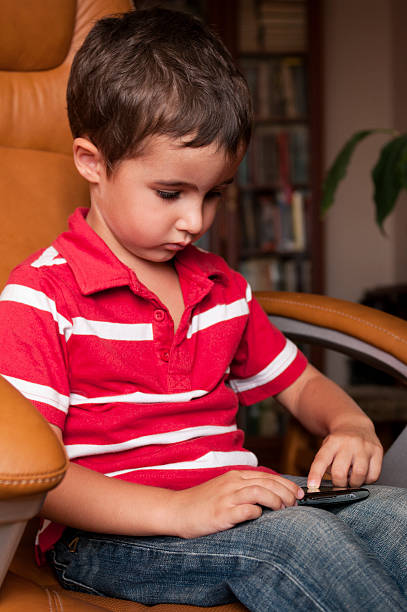 istock Little boy play smartphone game in leather chair 155697352