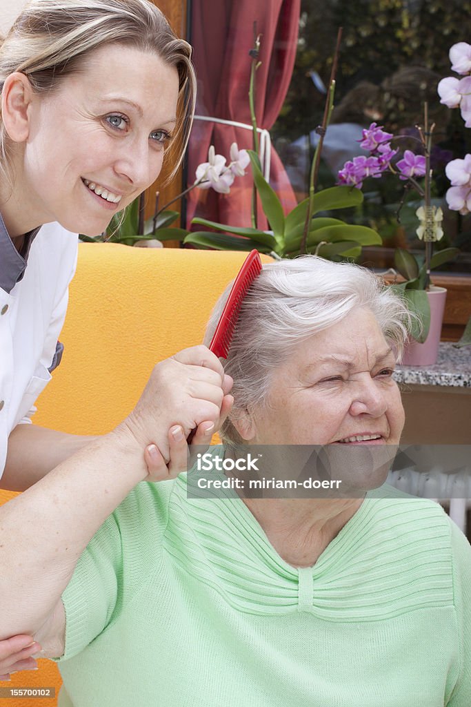 Personal de enfermería combs hair de un senior - Foto de stock de 70-79 años libre de derechos
