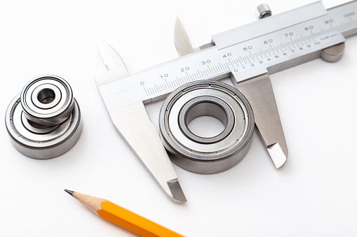Calipers and ball bearings on white background.
