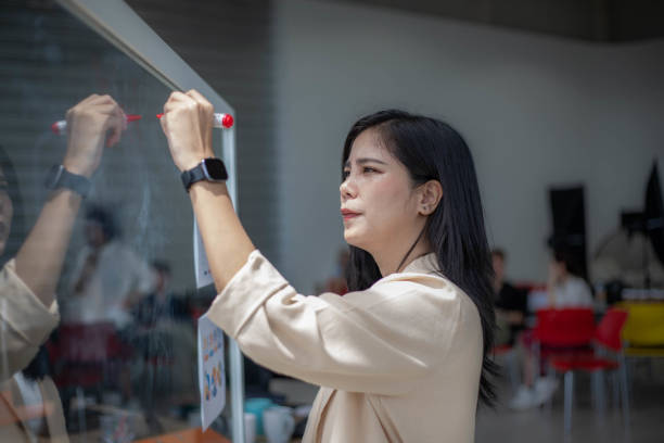 istock Young business woman writing on a transparent board 1557062536
