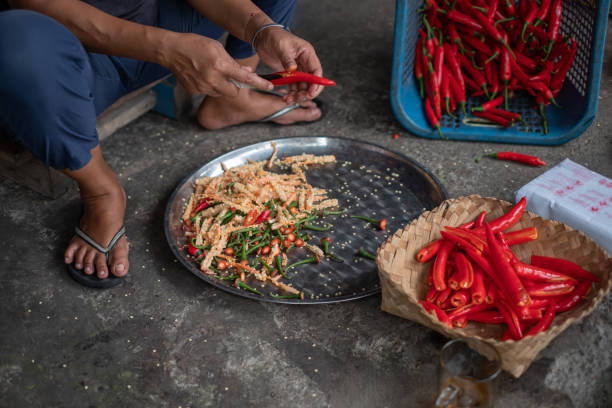 Close-up shot of unrecognizable Indonesian woman removing red chili seed while sitting on the floor