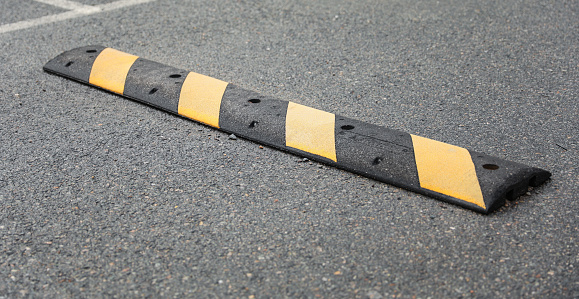 speed bump on a street symbolizes traffic control, caution, and slowing down for safety. It represents the need to be vigilant and considerate of others