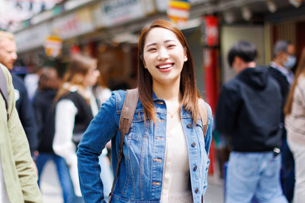 istock Asian woman with backpack smiling at the camera 1557210664
