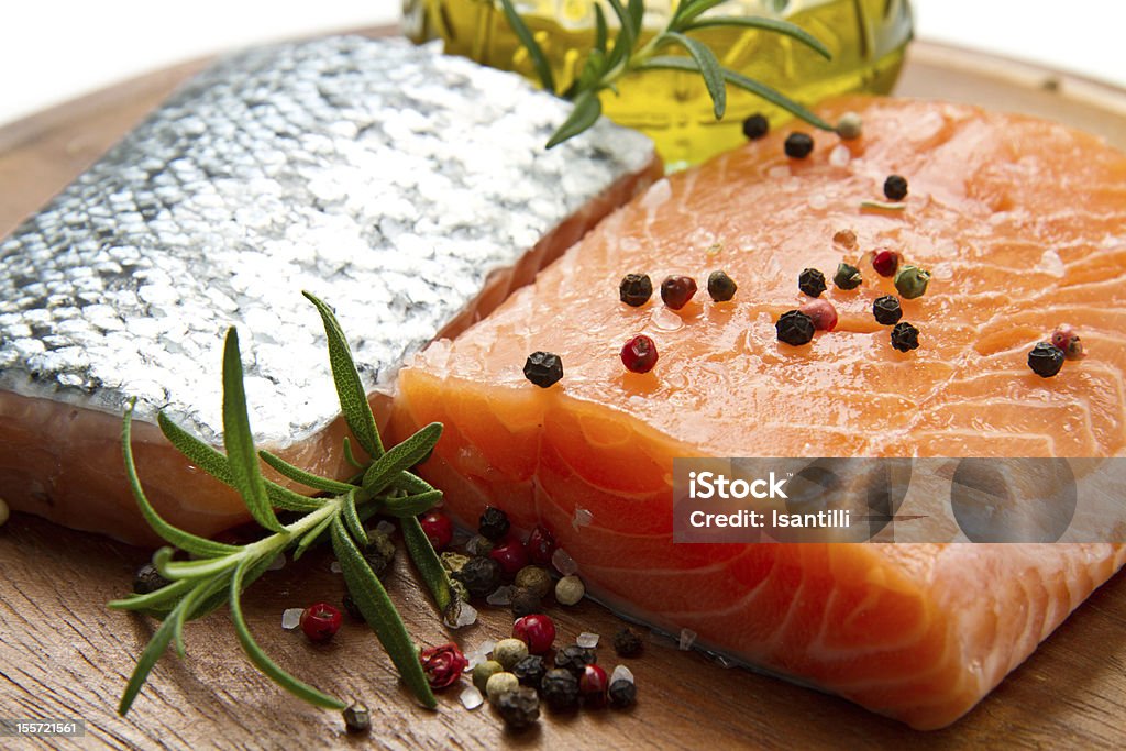 Fresh salmon fillet on wooden board Fresh salmon fillet on wooden board with pepper and rosemary Cooking Oil Stock Photo
