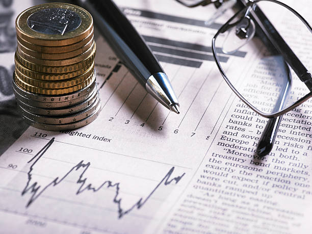 A financial chart with coins, glasses and pen