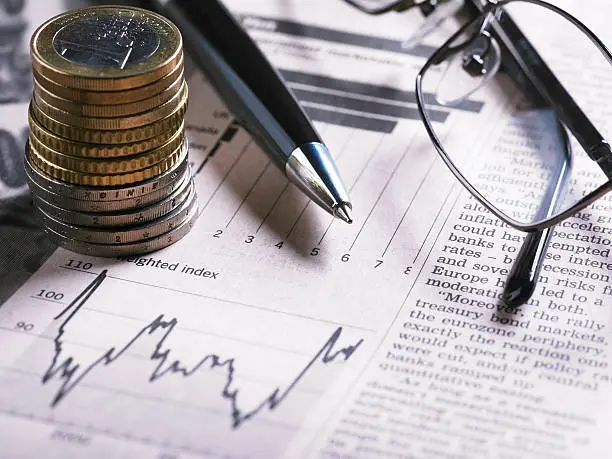 Photo of A financial chart with coins, glasses and pen