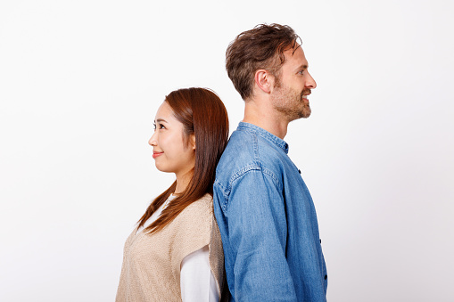 Portrait of Asian woman and Caucasian man standing back against back