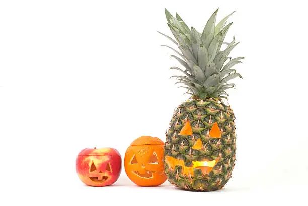 Jack-o-lanterns made from pinapple , apple and orange creating tropical helloween decoration