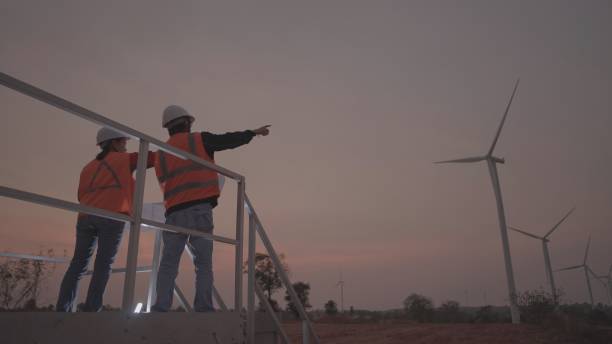 istock Team engineer working on a power generation project or contractor or civil engineer or partnership, discuss and agree on an installation plan wind turbines in area on the blueprints or talking about plan maintenance of the generator system. Overtime work, 1557263304