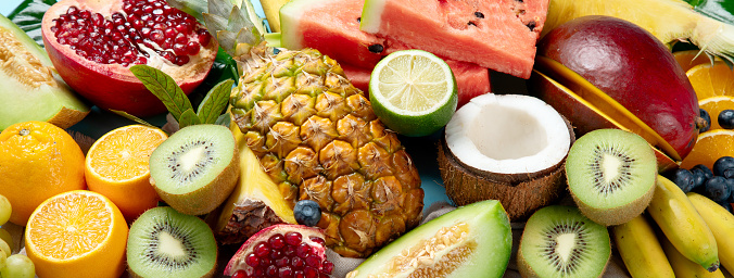 Fresh fruits assorted on a blue background. Vitamins natural nutrition concept. Top view. Panorama.