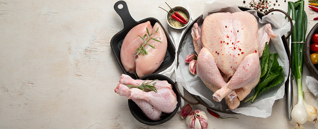 Poultry. Carcass and meat in pieces with vegetables. Meat composition on a white background. Top view. Panorama with copy space.