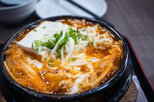 Close up of Kimchi Jjigae or Kimchi soup in a black clay pot. It's a Korean traditional food.