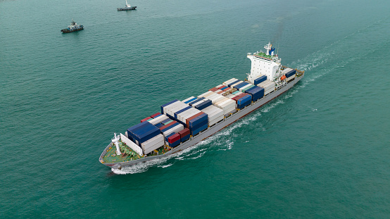 cargo container ship sailing full speed in sea to import export goods and distributing products to dealer and consumers across worldwide, by container ship Transport open sea. aerial view