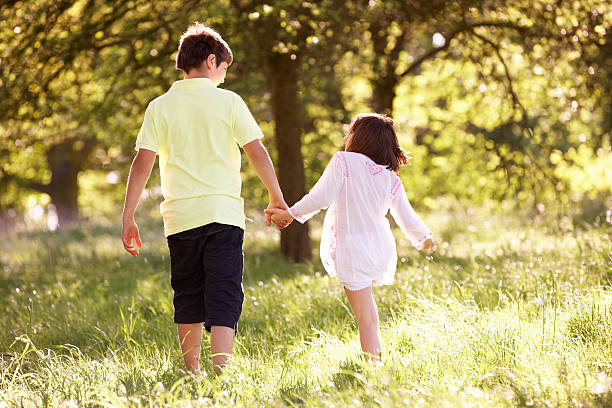 istock Boy And Girl Walking Through Summer Field Together 155728063