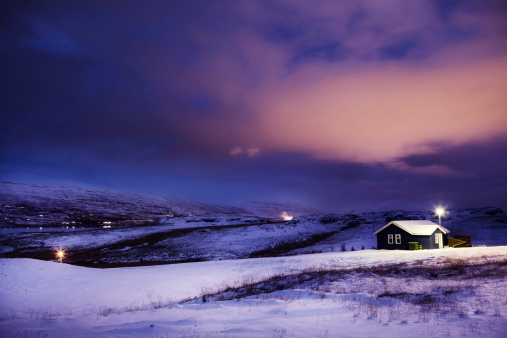 Photo taken in the middle of the night on a quaint hill in the winter. Setting is Akureyri, Iceland, but could pass as any rural, winter scene. Photo includes a view of surrounding hills.
