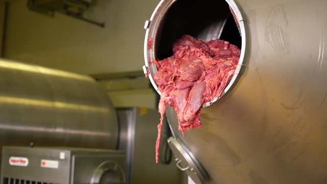 Meat defroster processing on factory. Meat falling in huge metal container.