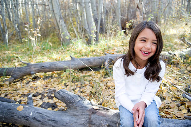 istock Beautiful young girl sitting on log 155735920