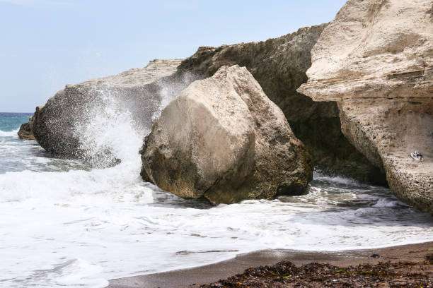 Waves crashing colorful rocks on the shore in Los Escullos Beach, Almeria, Cabo de Gata