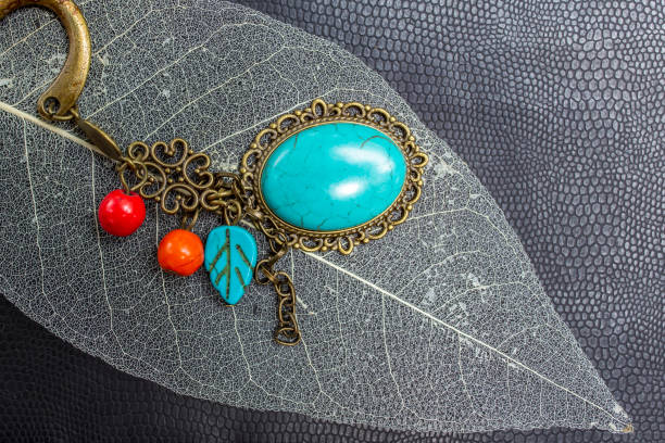 istock turquoise stone brooch  on skeleton leaf texture, soft focus 1557365531