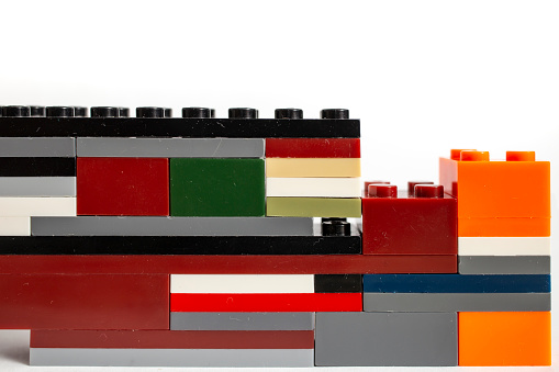 Colorful plastic bricks stacked on white background, playful toys border, close up texture