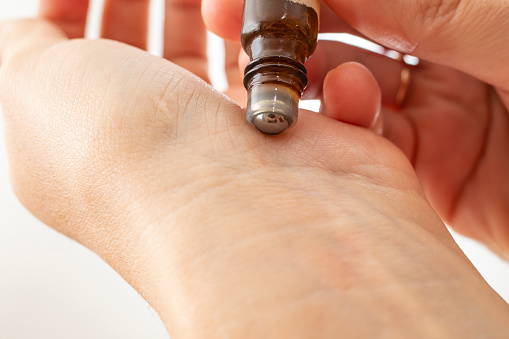 woman hands testing a roll on with essential oil , applying liquid on the wrist, soft focus