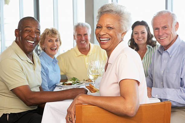 Friends Having Lunch Together At A Restaurant Group Of Senior Friends Having Lunch Together At A Restaurant Smiling at camera 65 69 years stock pictures, royalty-free photos & images