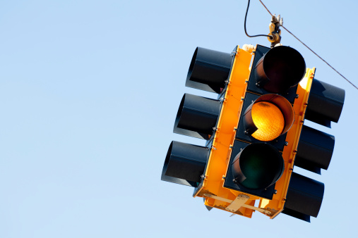 A yellow light traffic signal with blue sky copy space