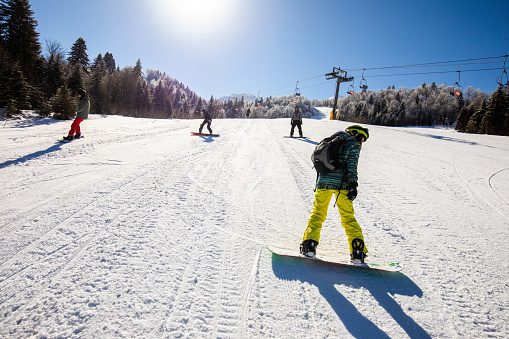 Group of people snowboarding in winter day on a ski slope. Copy space.