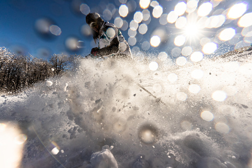 Young woman having fun while skiing and splashing snow on a mountain. Copy space.