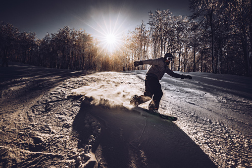 Male snowboarder moving down the hill on a mountain. Copy space.
