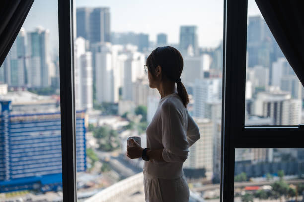 istock Urban Euphoria: An Asian Woman's Coffee Journey with Cityscape 1557383508