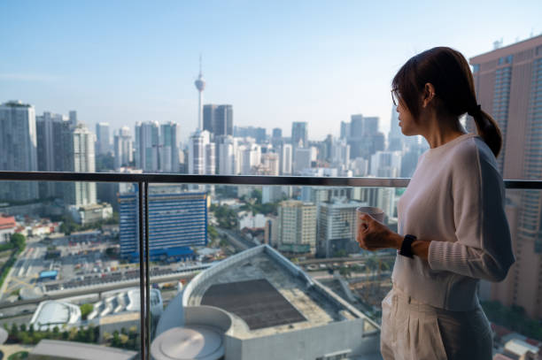 istock Balcony Brews: Asian Woman's Serene Coffee Experience with a View 1557383534