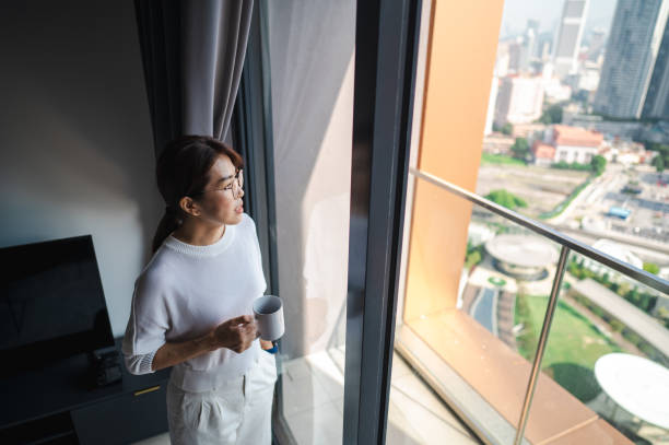 istock The Perfect Blend: An Asian Woman's Coffee Pause Overlooking the City 1557388308