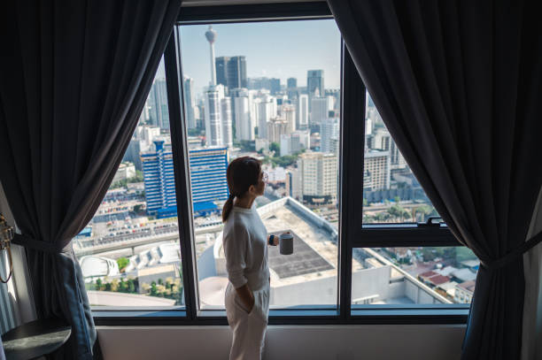 istock Serene City Views: An Asian Woman's Coffee Break on the Balcony 1557389960