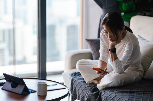 istock Work and Relaxation: An Asian Female Balances on the Sofa 1557390479