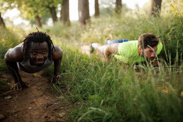 A young man is performing tricep dips on parallel bars set up in a natural forest environment. This outdoor workout focuses on enhancing upper body strength, particularly targeting the triceps, shoulders, and chest muscles. Combining fitness with a refreshing natural atmosphere, the activity promotes a healthy and active lifestyle.