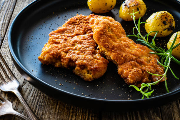 côtelette de porc frit panée avec pommes de terre frites et légumes frais sur table en bois - wiener schnitzel photos et images de collection