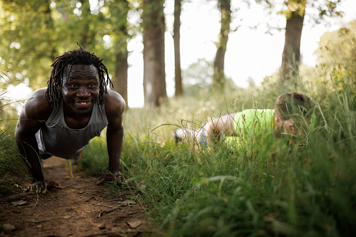 Young male friends doing push-ups in nature