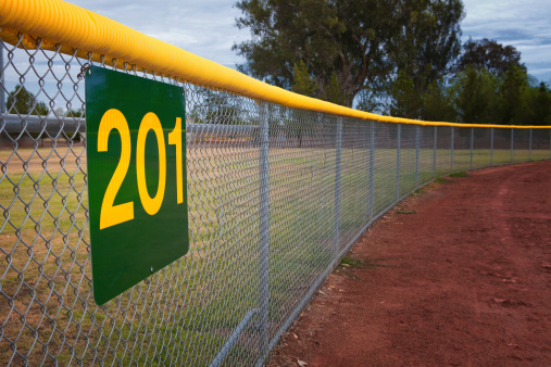 Little league baseball fence with a distance marker sign.