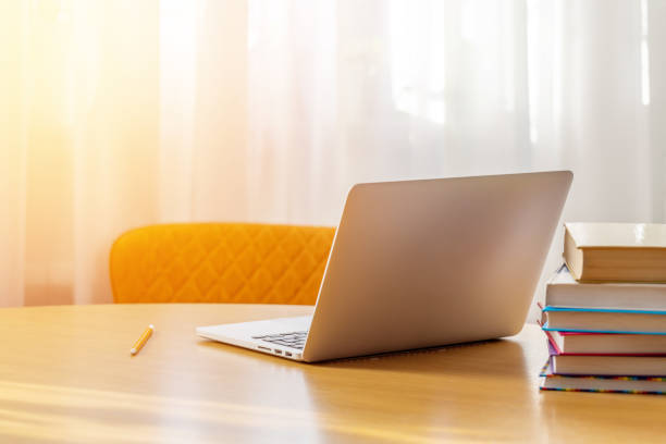 istock Laptop on a desk with stack of books 1557460716