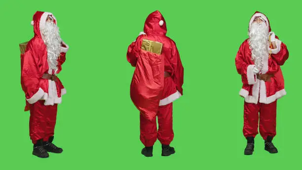 Santa choirmaster chief in red suit accompany professional orchestra as professional musician, full body greenscreen. Person with presents bag conducting band, musical director.