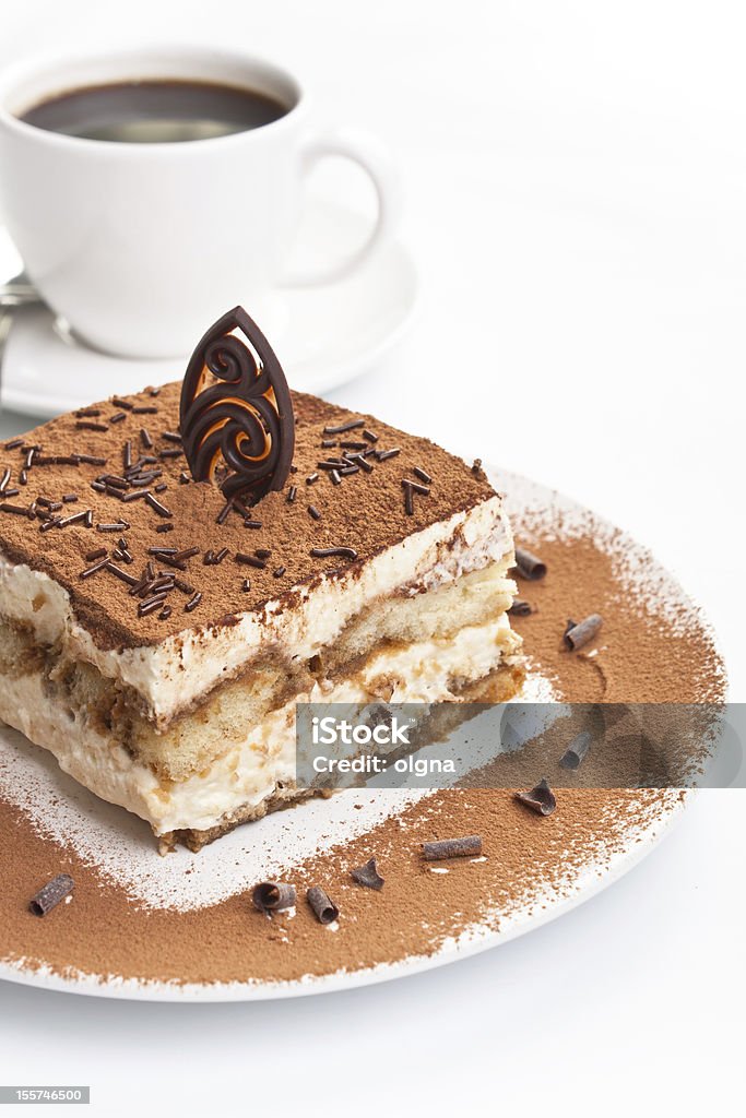 Portion of italian tiramissu cake Slice of homemade italian tiramisu dessert served on a plate and a cup of coffee on white background Brown Stock Photo
